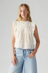 Blusa blanca sin mangas con cuello alto y detalles de encaje y volados.