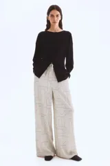 Pantalón de corte amplio y tiro alto, con cintura elástica y cordón de ajuste. Presenta un estampado geométrico en blanco y negro con líneas finas y formas entrelazadas.