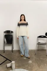 Sweater de punto color crudo con diseño geométrico en negro, gris y beige en la parte superior.