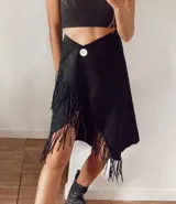 Pollera cruzada color verde militar, de largo midi, con detalle de flecos largos en el borde. Presenta un botón oscuro en la cintura para el ajuste.