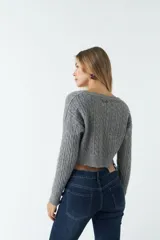 Sweater corto gris de punto trenzado con escote redondo amplio y mangas largas texturadas.