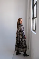 Vestido largo negro con estampado floral en tonos beige, corte amplio, cuello mao y mangas 3/4 acampanadas.