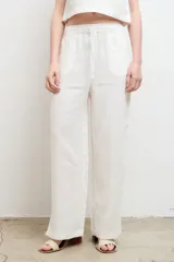 Pantalón color arena, de corte recto y tiro alto, confeccionado en lino.