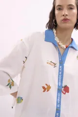 Camisa blanca con cuello azul y estampado de motivos veraniegos.