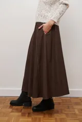 Falda larga de jean azul oscuro, corte acampanado con paneles y costuras visibles.