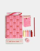 Set de librería en estuche transparente con borde rosado y tiras. Incluye cuaderno A5 de tapa dura con espiral de 80 hojas rayadas, anotador espiralado de hojas lisas, 5 mini resaltadores (amarillo, rosa, celeste, lila y naranja), regla de 15 cm, lápiz de grafito, goma y sacapuntas.