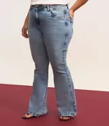 Pantalón de jean azul claro, modelo flare, con cintura elástica, trabillas para cinturón, bolsillos delanteros y traseros, y botón en forma de flor.