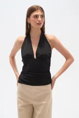 Top negro sin mangas de poliamida, con frunces, corte al cuerpo y escote halter profundo.