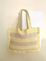 Bolso tipo tote tejido a crochet, con hilo 100% algodón, a rayas horizontales color crema y lila, con volados en los bordes y manijas reforzadas.