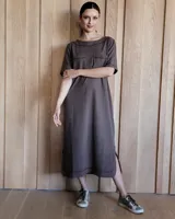 Vestido midi negro con cuello redondo y mangas cortas. Presenta dos bolsillos cuadrados en el pecho y ribetes blancos en cuello, mangas, bolsillos y ruedo.