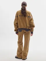 Pantalón de denim color marrón claro, de tiro alto, corte amplio y pinzas en la cintura.