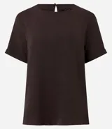 Blusa blanca de poliéster con cuello redondo, mangas cortas, cierre trasero en forma de gota, pequeñas aberturas laterales y acabados en pespuntes en las mangas y el cuello.