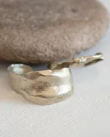 Brazalete rígido plateado con textura irregular.