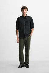 Pantalón verde oscuro con textura de rayas verticales, corte relaxed fit, cintura elástica ajustable con cordón, bolsillos delanteros y bolsillo trasero de parche.