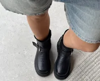 Bota corta de cuero negro con punta cuadrada, hebillas laterales y suela artesanal de cuero.