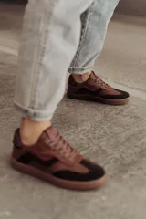 Zapatillas bajas de cuero color marrón con suela de goma color caramelo y cordones marrones.