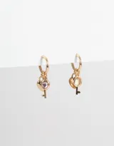 Aros dorados tipo argolla con dije de corazón con strass rosa y llave colgando.