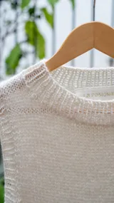 Chaleco tejido color crema, con cuello alto y sin mangas.