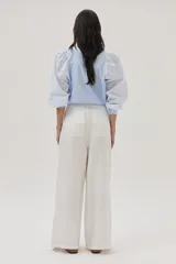 Blusa celeste a rayas verticales blancas, con cuello mao con lazos, mangas abullonadas y corte imperio.