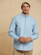 Camisa de algodón azul claro, con corte clásico y bolsillo en el pecho.