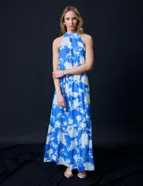 Vestido largo de gasa con estampado floral en tonos celeste y blanco. Tiene escote halter, cintura elastizada con lazo de ajuste, abertura en la espalda con botones y forro interno.