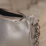 Cartera tipo baguette de cuero color rojo brillante, con correa de cadena plateada.