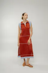 Vestido midi de punto color ladrillo, con cuello polo, sin mangas y diseño calado. Presenta rayas horizontales en color celeste en el ruedo, la cintura y el pecho.