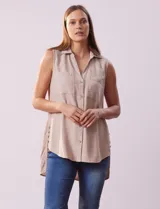 Camisa sin mangas color beige, marca Zac & Rachel, confeccionada en lino. Presenta escote en V, abertura frontal con botones, dos bolsillos delanteros y terminación con botones en los laterales.