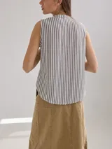 Camisa sin mangas a rayas verticales blancas y grises, con cuello mao y cierre parcial con botones.