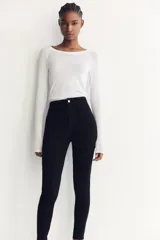 Jeans skinny de tiro alto en denim azul oscuro, con cinco bolsillos y cierre frontal con cremallera y botón metálico.