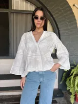 Blusa blanca de algodón con bordado tipo broderie, escote en V y mangas 3/4.