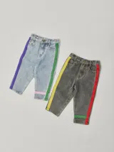 Pantalón de jean celeste con efecto lavado, corte recto y largo a la rodilla. Presenta una cinta vertical color violeta en la pierna izquierda, una cinta vertical color verde en la pierna derecha y una cinta horizontal color rosa en la parte inferior de ambas piernas.