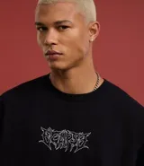 Remera negra de algodón con corte oversized, cuello redondo, mangas cortas y estampa tribal blanca en el pecho.