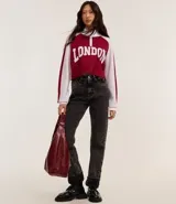 Suéter corto de punto con cuello alto y medio cierre con cremallera. Tiene mangas largas con sisa raglán y lettering "London" en el frente.