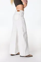 Pantalón jean color beige, de corte recto y tiro alto, con bolsillos delanteros y traseros, y detalle desflecado en los laterales.