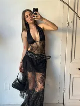 Vestido largo negro de encaje con forro corto, escote halter, espalda descubierta y cinturón con hebilla metálica y tachas.