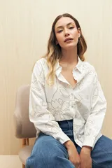 Camisa blanca de manga larga confeccionada en algodón liviano con calados florales. De corte clásico y botones frontales.