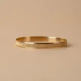 Pulsera rígida dorada con textura satinada y otra con textura martillada.