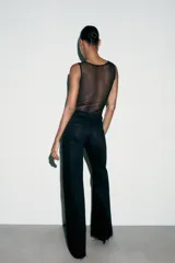 Body negro de cuello redondo y sin mangas, con parte superior de tul transparente y cierre inferior con broches a presión.