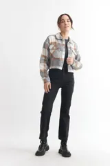 Chaqueta corta a cuadros grises, marrones y blancos, con cuello clásico, cierre abotonado, mangas largas y dos bolsillos con solapa en el pecho.