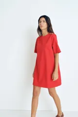 Vestido corto rojo con cuello redondo y manga corta. Presenta detalle de botones dorados en el hombro.