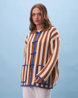 Cárdigan tejido a rayas verticales color marrón y beige, con cuello marrón, cierre con nudos azules y bolsillos frontales ribeteados en azul.