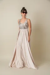 Vestido largo de fiesta color champagne, con corpiño de lentejuelas plateadas, falda de satén liso y lazo de satén en la cintura. Corsé de tul bordado. Talle único adaptable de S a L.