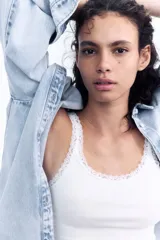 Musculosa blanca de algodón acanalado con breteles finos y escote redondo pronunciado con ribete de encaje.