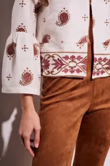 Blusa blanca con estampado de cachemir en color marrón y bordado floral en el ruedo y mangas acampanadas.