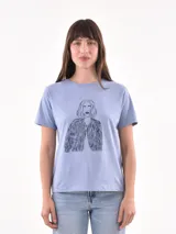 Remera celeste con estampado de una figura femenina con chaqueta.