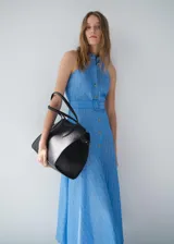 Vestido midi de algodón y lino, color celeste con rayas verticales blancas. Presenta cuello camisero, diseño sin mangas con tirantes anchos, cierre de botones frontales, cinturón con hebilla y falda evasé.