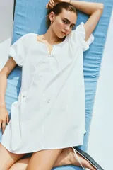 Vestido corto evasé de algodón blanco, con mangas globo cortas de diseño raglán, escote redondo con cordón para ajustar y corte holgado.