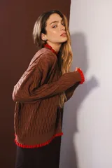 Sweater tejido rojo con cuello alto y puños con volados azules.