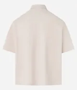 Camisa beige de algodón texturizado, corte boxy, manga corta, cuello inglés y abotonadura frontal.